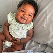 Khani joined the competition — help win amazing prizes! baby, blanket, child, clothing, cozy, curly_hair, cute, diaper, fabric, face, hand, happy, indoor, infant, person, sitting, skin, smiling, soft, toddler