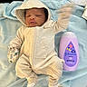 Jordan is registered to the contest to win money with this photo: baby, infant, blanket, bottle, lotion, onesie, hood, mittens, hand_motion_blur, blue, purple, soft_texture, lying_down, closeup, indoor, person, newborn, cute, sleep_aid, baby_care