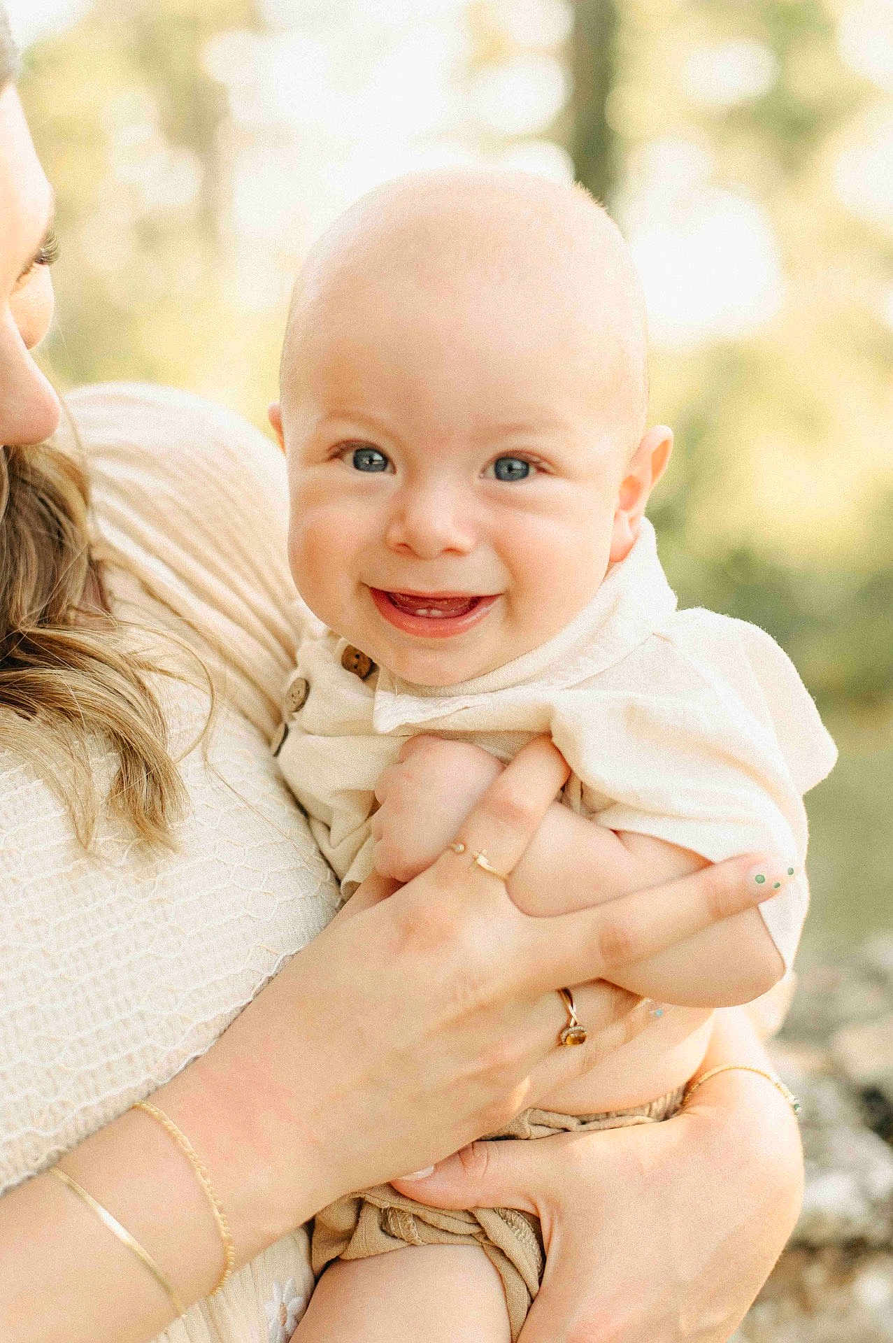 Daniel is registered to the contest to win money with this photo: baby, smiling, child, person, holding, adult, hand, face, blue_eyes, outdoor, nature, soft_light, happy, skin, clothing, portrait, closeup, cute, warm, family