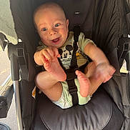 Daniel joined the competition — help win amazing prizes! baby, stroller, child, diaper, mickey_mouse, infant, happy, smiling, hand, foot, clothing, seatbelt, black_stroller, person, cute, playful, face, indoors, light, expression