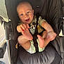 baby, stroller, child, diaper, mickey_mouse, infant, happy, smiling, hand, foot, clothing, seatbelt, black_stroller, person, cute, playful, face, indoors, light, expression
