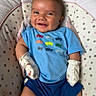baby, smiling, blue_shirt, mittens, baby_seat, polka_dots, infant, child, cute, happy, apparel, clothing, shorts, toddler, face, portrait, indoor, resting, comfort, playful