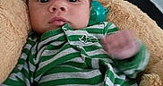 Mark joined the competition — help win amazing prizes! baby, infant, striped_clothing, green_clothing, gray_clothing, face, expression, cushion, plush, indoor, person, young_child, lying_down, hand, furniture, soft_texture, blanket, close_up, casual, comfortable