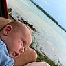Murphy joined the competition — help win amazing prizes! baby, infant, close_up, face, head, skin, outdoor, lake, water, nature, grass, sky, person, resting, curious, blue_clothing, adult, lap, calm, serene