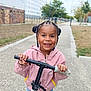 Valentina-Maria a rejoint le concours — aidez-le/la à gagner de superbes lots ! blue_jeans, braided_hair, casual_clothing, child, daylight, fun, happy, outdoor, park, pathway, person, pink_jacket, play, recreation, scooter, smiling, transportation, trees, urban, young_child
