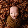 baby, blanket, brown, child, close_up, cozy, eyes, face, fluffy, infant, lying_down, newborn, open_mouth, photography, portrait, sleepy, studio, swaddled, textured, wrapped