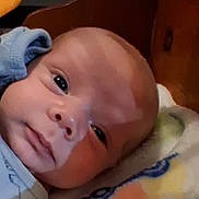 Wyatt is registered to the contest to win money with this photo: baby, infant, child, portrait, close_up, face, eyes, looking_at_camera, lying_down, blanket, blue_clothing, head, indoors, cozy, warm_lighting, soft_surface, baby_hat, curious, photography, close_portrait