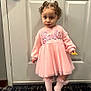 barbie, carpet, child, clothing, curly_hair, cute, door, expression, fashion, floor, girl, holding, indoors, pigtails, pink_dress, portrait, snack, socks, standing, young_child