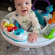 Tucker joined the competition — help win amazing prizes! baby, child, smiling, indoor, activity_center, toy, play, happy, person, infant, colorful, seat, carpet, hand, face, clothing, floor, cute, joy, expression
