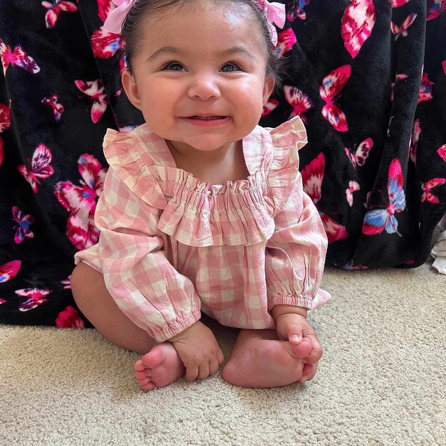 Rosemarie joined the competition — help win amazing prizes! baby, child, smiling, pink_bows, pink_outfit, checkered_clothing, carpet, butterfly_pattern, black_blanket, happy, cute, portrait, indoor, sitting, infant, toes, long_sleeves, hair_bows, cheerful, adorable
