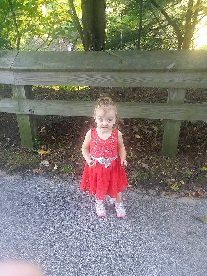 Annabelle is registered to the contest to win money with this photo: child, clothing, day, dress, fun, girl, grass, outerwear, pattern, person, pink, plant, play, recreation, smile, standing, toddler, tree, vacation