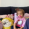 Victoire participe au concours pour gagner de l'argent avec cette photo : toddler, child, pacifier, hello_kitty, pink_shirt, plush_toys, bed, couch, toy, stuffed_animal, yellow_pillow, pink_pillow, hair_tie, indoor, person, sitting, cute, playful, casual, relaxed