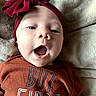 baby, infant, child, portrait, face, wide_eyes, open_mouth, smiling, headband, bow, burgundy, shirt, clothing, blanket, cozy, indoor, close_up, lying_down, couch, happy