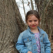 Emma joined the competition — help win amazing prizes! child, girl, denim_jacket, floral_shirt, tree_trunk, outdoor, nature, smile, young, portrait, casual_clothing, spring, brown_hair, standing, background, branches, bark, forest, daylight, person