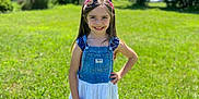 Emma is registered to the contest to win money with this photo: child, girl, smiling, outdoor, grass, greenery, sunny, dress, denim, headband, crocs, happy, portrait, nature, summer, young, person, blue_sky, casual_clothing, standing