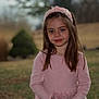 Emma is registered to the contest to win money with this photo: child, girl, pink_sweater, headband, outdoor, nature, portrait, young, smile, long_hair, standing, grass, trees, blurred_background, casual_clothing, cute, youth, person, fall, daylight