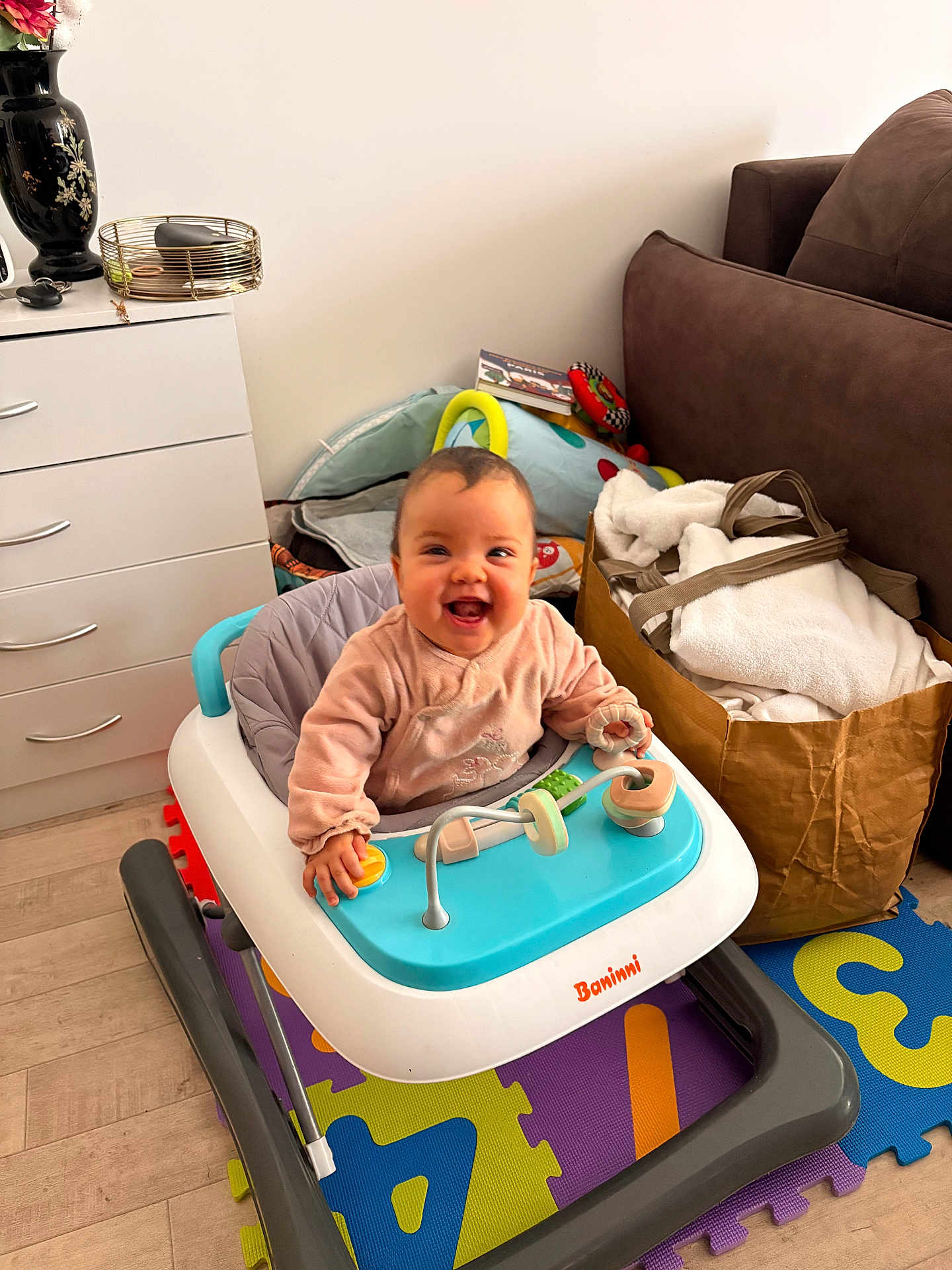Loona a rejoint le concours — aidez-le/la à gagner de superbes lots ! baby, smiling, walker, toy, playmat, living_room, couch, paper_bag, blanket, drawer, vase, flooring, infant_clothing, happy, portrait, playtime, seat, person, cute, indoor