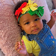 Jewel is registered to the contest to win money with this photo: baby, infant, child, headband, hair_bow, colorful_bows, denim_overalls, yellow_shirt, pink_pillow, plush_pillow, bed, blanket, hand, eyes, face, cute, portrait, closeup, soft_texture, relaxed_pose