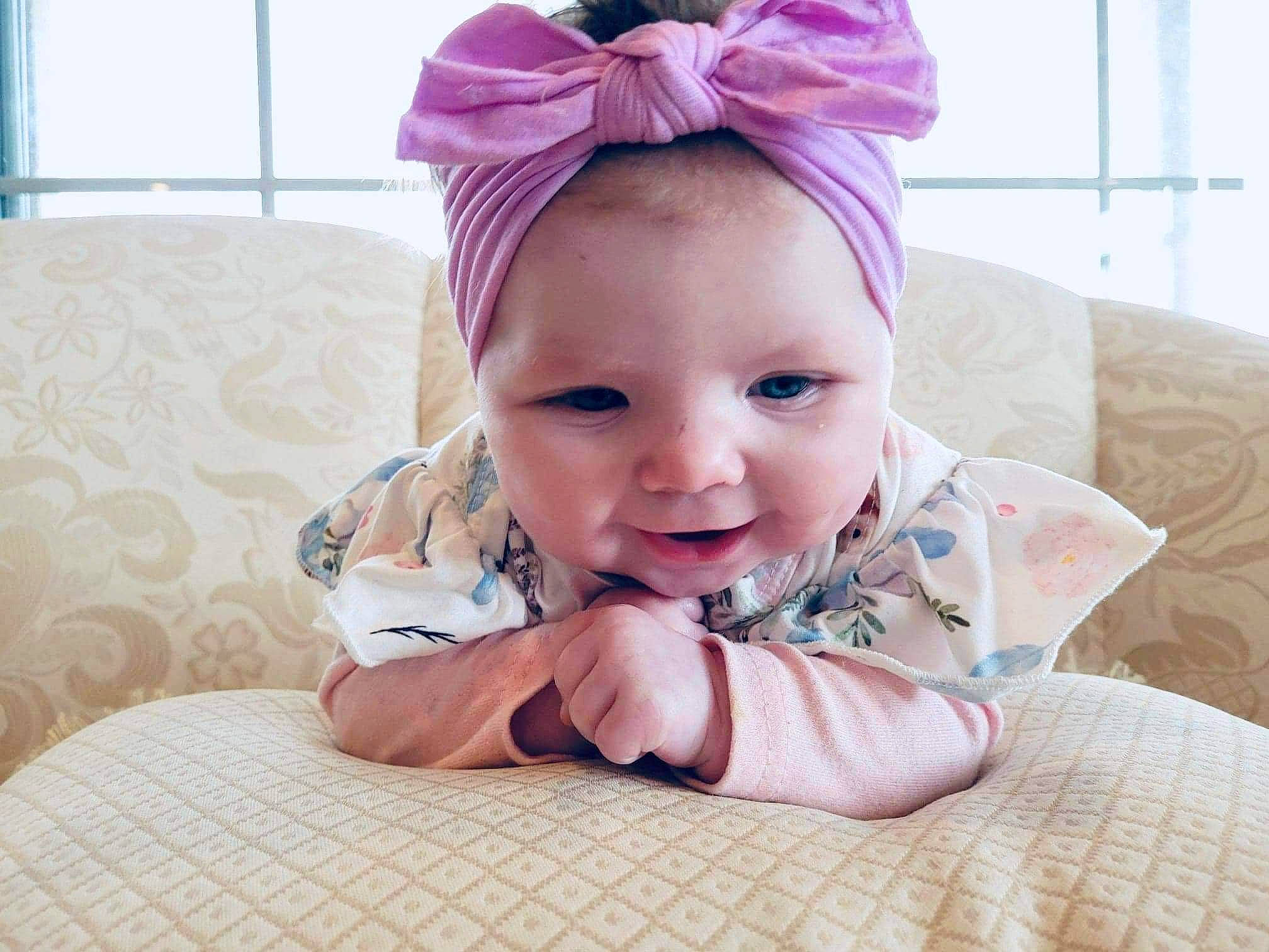 Delilah is registered to the contest to win money with this photo: baby, baby_toddler_clothing, chin, comfort, ear, eyebrow, eyelash, face, happy, headband, headpiece, lip, magenta, neck, person, pink, purple, smile, textile, toddler