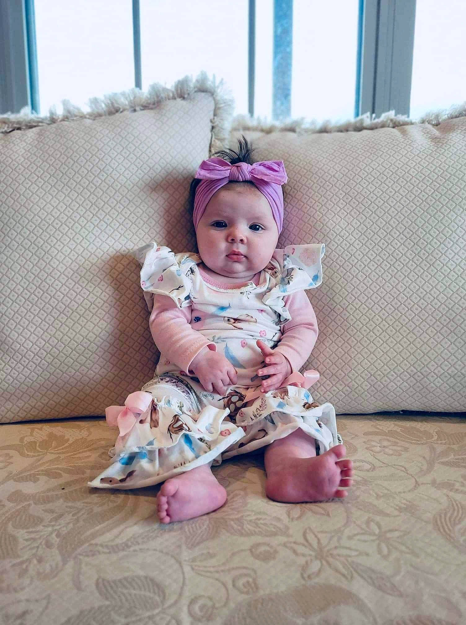 Delilah joined the competition — help win amazing prizes! baby, baby_toddler_clothing, cheek, comfort, couch, dress, embellishment, eye, face, fashion_accessory, flooring, head, headwear, magenta, pattern, person, pink, purple, sleeve, textile