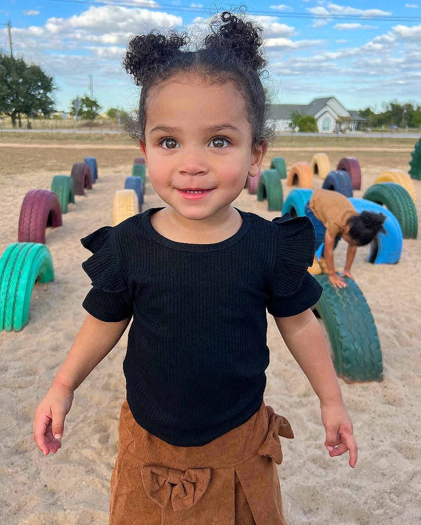 Leilani is registered to the contest to win money with this photo: architecture, building, child, clothing, face, female, girl, hair, head, machine, nature, outdoors, pants, person, photography, portrait, shorts, summer, t_shirt, wheel