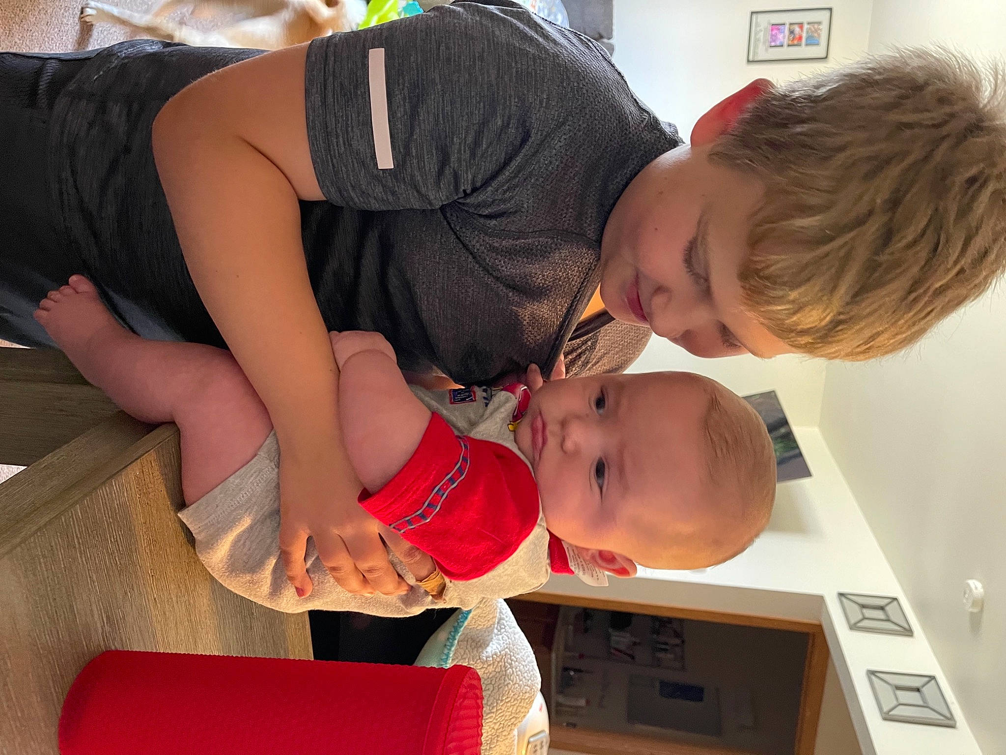 Trevor is registered to the contest to win money with this photo: baby, carmine, child, comfort, elbow, finger, fun, hairstyle, happy, human_leg, joint, lap, person, room, sitting, t_shirt, thigh, toddler, vacation