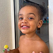 Callum participe au concours pour gagner de l'argent avec cette photo : child, toddler, smiling, lollipop, indoors, bare_chested, hand, face, happy, person, doorway, wall, hair, teeth, skin, fingers, mouth, expression, young_child, cute