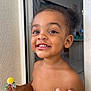 child, toddler, smiling, lollipop, indoors, bare_chested, hand, face, happy, person, doorway, wall, hair, teeth, skin, fingers, mouth, expression, young_child, cute