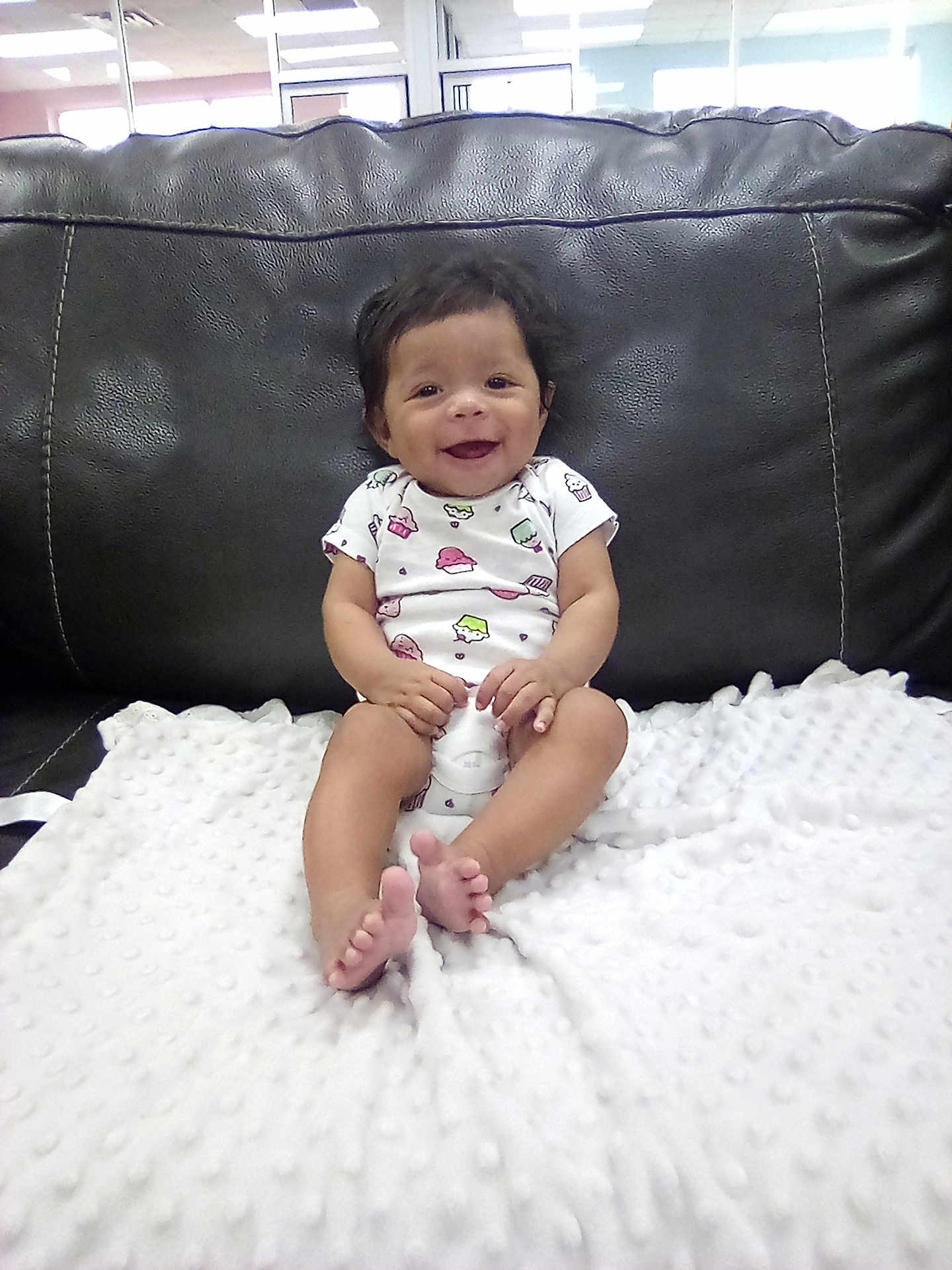 Lia Kalanie Rosalez joined the competition — help win amazing prizes! baby, child, smiling, sitting, blanket, couch, leather, onesie, indoor, happy, face, foot, hand, hair, infant, cute, texture, white, black, furniture