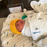 Ariel joined the competition — help win amazing prizes! newborn, baby, sleeping, blanket, yellow_hat, hospital_bassinet, pacifier, infant, swaddled, bed, cute, peaceful, child, face, headwear, cozy, soft, white, gray, pattern