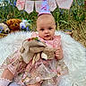 baby, infant, birthday_hat, pink_dress, plush_toy, bunny, blanket, flowers, banner, outdoor, grass, teddy_bear, cute, celebration, child, portrait, smiling, nature, happy, festive