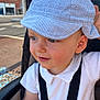 toddler, child, baby, hat, cap, blue_eyes, white_shirt, stroller, safety_straps, outdoor, urban, side_profile, smile, curious, face, person, daylight, street, casual_clothing, headwear