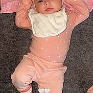 Nova is registered to the contest to win money with this photo: baby, infant, pink_clothing, headband, bib, socks, lying_down, carpet, blanket, cute, child, indoors, soft_lighting, portrait, small_heart_pattern, newborn, baby_girl, cozy, relaxed, adorable