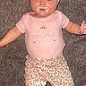 Nova is registered to the contest to win money with this photo: baby, infant, pacifier, headband, pink_clothing, floral_pants, socks, carpet, cute, lying_down, child, portrait, human, adorable, indoor, soft_texture, young_child, baby_girl, expression, face