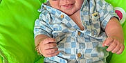 Ronnie Trevor is registered to the contest to win money with this photo: baby, child, sunglasses, blue_clothing, checkered_pattern, green_chair, smiling, barefoot, bracelet, indoor, cute, happy, infant, legs, reflection, relaxing, person, fashion, accessory, portrait