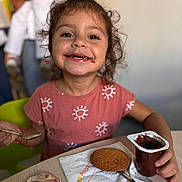 Ayla participe au concours pour gagner de l'argent avec cette photo : casual_clothing, child, chocolate, cookie, curly_hair, cute, dining, food, girl, happy, indoor, messy, napkin, person, pink_shirt, portrait, pudding, smiling, spoon, table