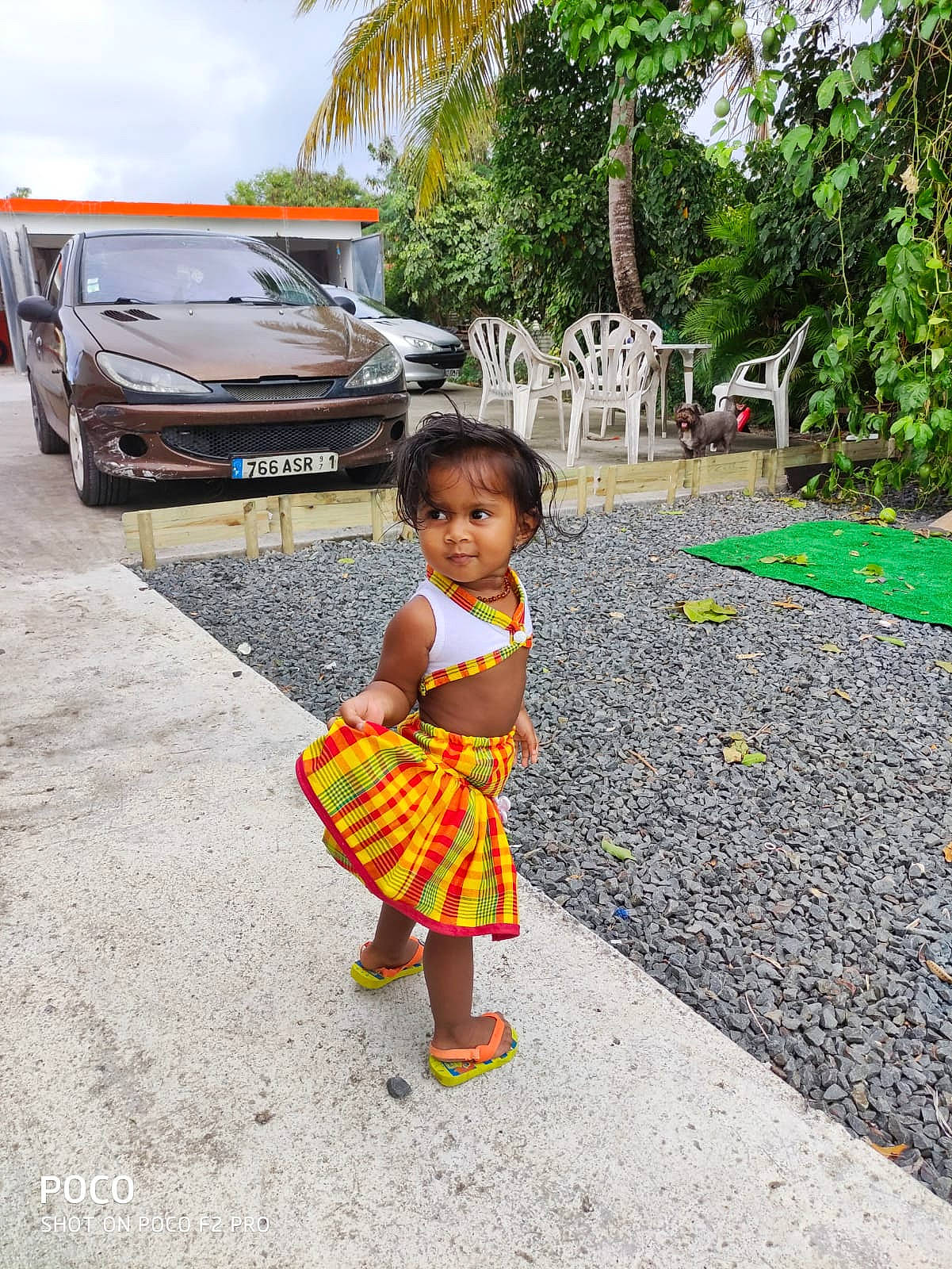 Djya participe au concours pour gagner de l'argent avec cette photo : automotive_tail_brake_light, baby, baby_toddler_clothing, child, compact_van, day_dress, driveway, microvan, minibus, minivan, one_piece_garment, palm_tree, pattern, person, plaid, sport_utility_vehicle, tartan, toddler, van, yard