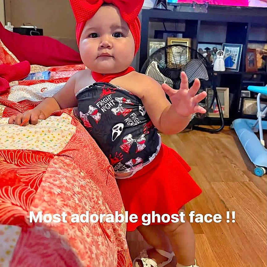 Adalina Lopez is registered to the contest to win money with this photo: baby, child, toddler, portrait, smiling, indoor, bedroom, bed, red_bow, costume, halloween, ghost, dress, shoes, television, elmo, furniture, wood_floor, social_media, text_overlay
