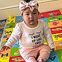 baby, child, infant, headband, pink, shirt, text, play_mat, colorful, alphabet, animal, floor, sitting, barefoot, indoors, cute, expression, person, young, casual_clothing