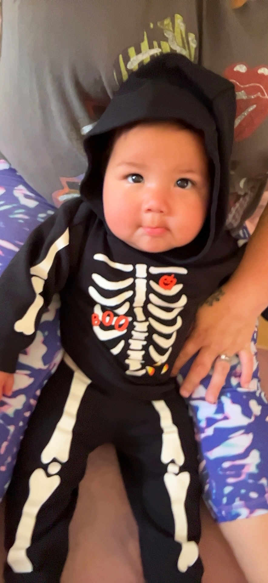 Charlee joined the competition — help win amazing prizes! baby, child, costume, skeleton, hoodie, black_clothing, sitting, person, legs, hand, colorful_leggings, face, cute, indoors, portrait, young_child, baby_clothes, halloween, expression, human