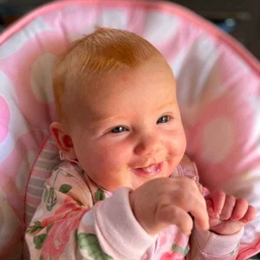 Ivy Rose is registered to the contest to win money with this photo: baby, bed, bodypart, crib, cushion, cutlery, face, finger, furniture, hand, happy, head, homedecor, infantbed, newborn, person, photography, portrait, smile, spoon