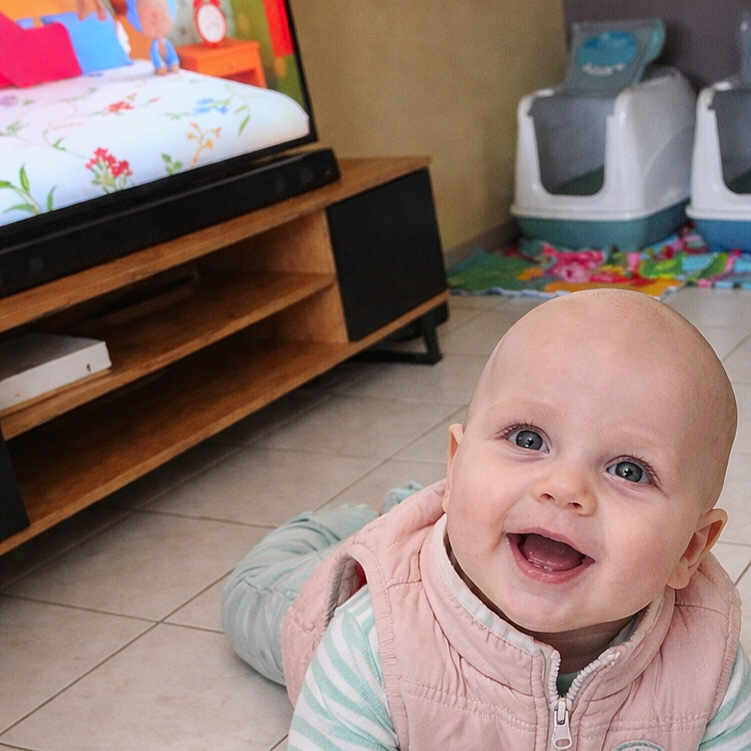 Lizyo participe au concours pour gagner de l'argent avec cette photo : baby, bald_head, big_eyes, cartoon, crawling, floor_tiles, furniture, happy, home_interior, indoor, infant, open_mouth, pet_litter_box, playmat, smiling_baby, striped_shirt, television, tiled_floor, vest, wooden_tv_stand