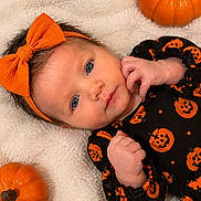 Ashlynn is registered to the contest to win money with this photo: baby, infant, child, portrait, halloween, pumpkin, bow, headband, onesie, orange, black, blanket, lying_down, indoors, close_up, face, eyes, smiling, cozy, festive