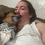 Copper is registered to the contest to win money with this photo: woman, dog, couch, blanket, indoor, affection, closeup, casual, relaxation, friendship, pet, snuggle, comfort, white_clothing, patterned_blanket, brown_furniture, portrait, human, animal, face