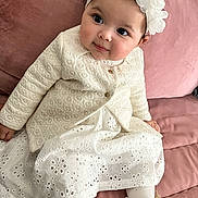 Tasnym Elazhar participe au concours pour gagner de l'argent avec cette photo : baby, child, girl, white_dress, headband, flower_crown, pink_couch, sitting, cute, portrait, footwear, jacket, tights, indoor, smiling, curly_hair, soft_lighting, closeup, happy, fashion