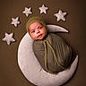 Rihan is registered to the contest to win money with this photo: baby, brown_background, child, cozy, cute, green_clothing, hat, infant, moon, newborn, nursery, pillow, plush, portrait, resting, sleepy, soft_texture, stars, studio_photo, swaddled