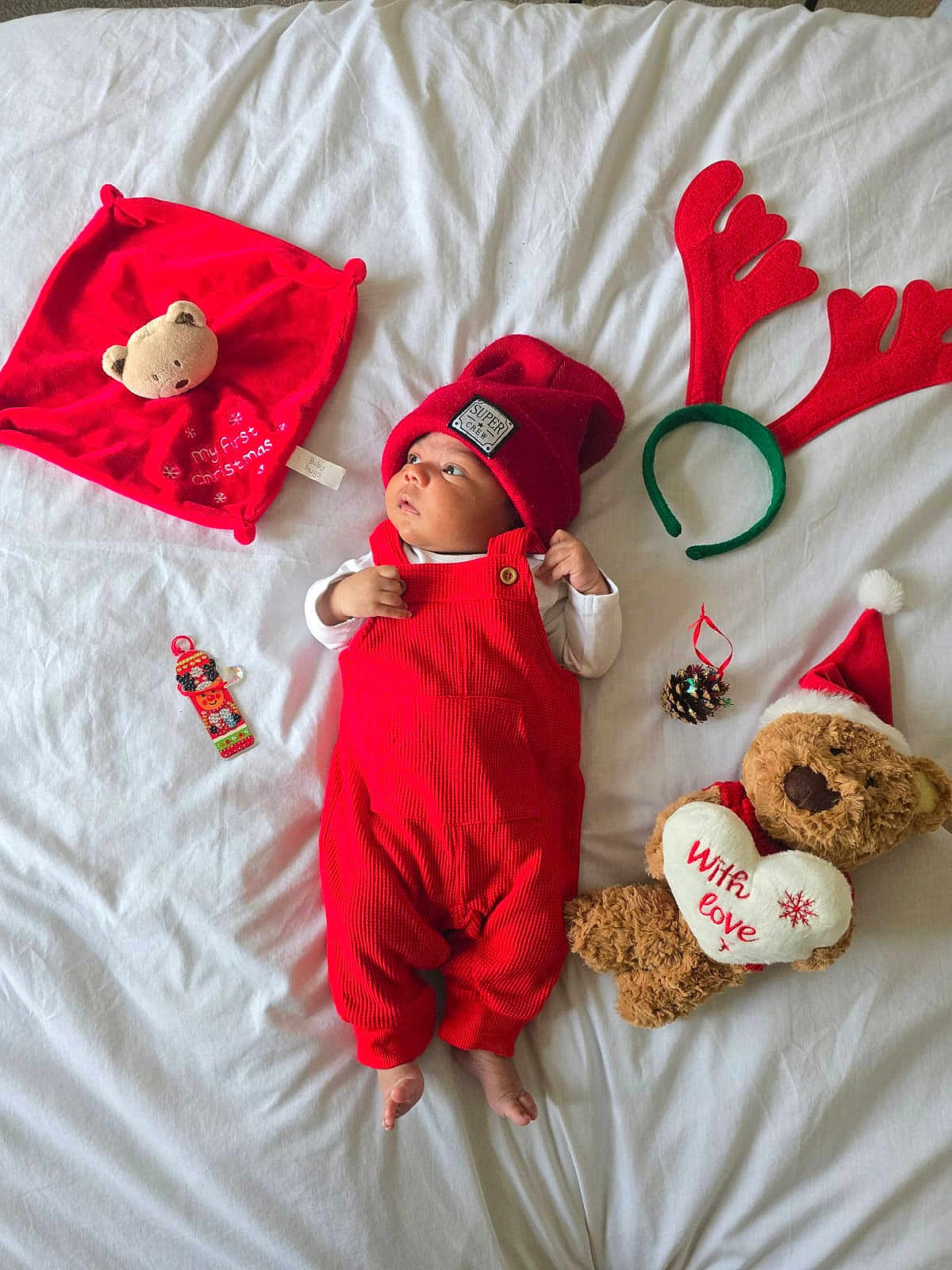 Rihan joined the competition — help win amazing prizes! baby, red_overalls, red_hat, teddy_bear, christmas, holiday, bed, white_bed_sheet, reindeer_antlers, pine_cone, plush_toy, infant, cute, festive, decorations, lying_down, soft_toy, christmas_hat, child, indoors