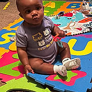 Major is registered to the contest to win money with this photo: baby, child, toy, foam_mat, colorful, alphabet, sitting, carpet, indoor, clothing, sock, nike, playtime, floor, cute, infant, person, head, hand, expression