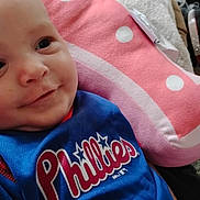 Andrew is registered to the contest to win money with this photo: baby, blanket, blue_jersey, child, closeup, clothing, cozy, face, head, indoor, infant, person, phillies, pillow, pink, polka_dot, portrait, resting, smiling, soft