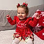 baby, child, christmas, red_dress, happy, smiling, hair_bows, couch, pillow, holiday, festive, indoor, tights, sitting, cute, face, person, celebration, christmas_decor, winter